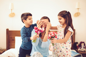 Kids giving their mother flowers to surprise her on Mother's Day